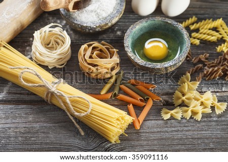 A set of raw pasta and addons on wooden table. Studio picture