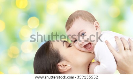 happy mother kissing her baby over green lights