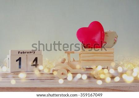 double exposure photo of February 14th wooden vintage calendar with wooden toy truck with hearts. valentine's day celebration concept. vintage filtered