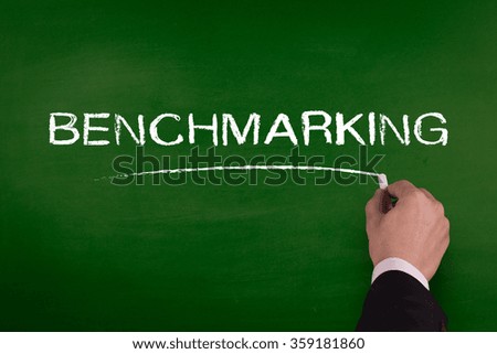 A businessman is writing BENCHMARKING concept on blackboard.