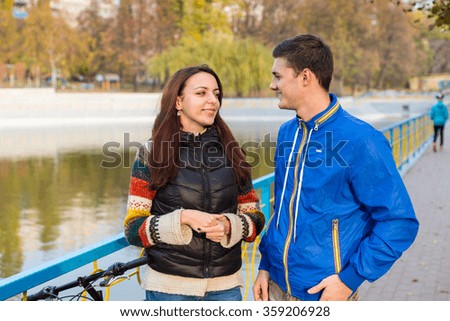 Waist Up of Young Couple Talking Together on Waterfront Pathway with Colorful Railing in Urban Park on Autumn Day