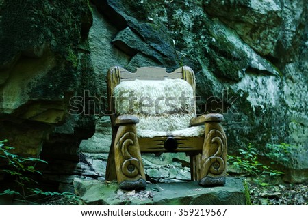 One big wooden cut beautiful arm chair as forest queen fairytale throne standing in wood with no people outdoor on grey stone natural background, horizontal picture