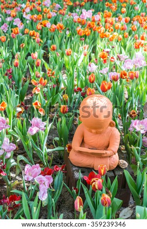 Clay dolls the novice reading a book on tulips background in the garden,