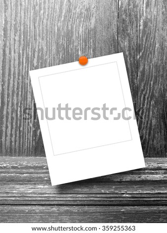 Close-up of one square instant photo frame with pin on monochrome wooden background