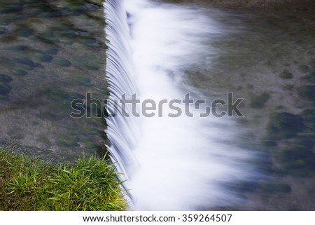 long expo of little falling water and green grass