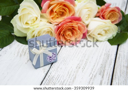 Beautiful roses and gift box on a wooden background