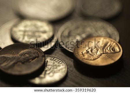 Close up of Coins of American currency. Quarters, dimes, and pennies on a desk. Focus macro leans on the detail of the pennies.