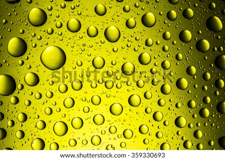 Yellow glass surface covered with water drops texture.