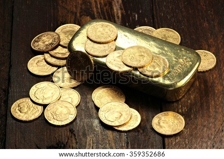 swiss vreneli gold coins and a gold ingot on wooden background Royalty-Free Stock Photo #359352686