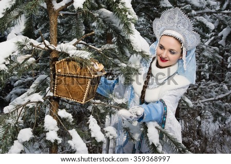 Russian Christmas characters: Snegurochka (Snow Maiden) with gifts bag in the winter forest