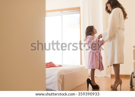 Little girl wearing heels with her mother in bedroom Royalty-Free Stock Photo #359390933