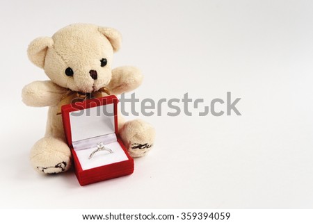 stylish luxury ring with diamond in red box and teddy bear on white background, valentine's day concept