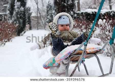 A man pulls a sledge with little toddler boy who is sitting on the sledge and falling from it in the snow, the moment of falling, family winter concept