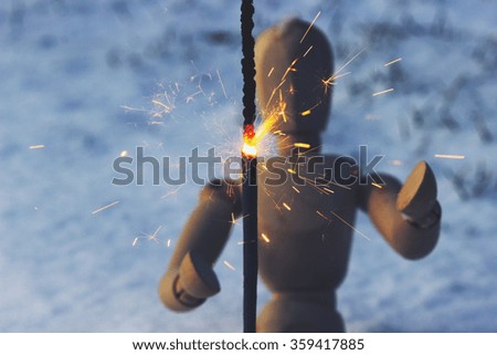 Lit sparkler and in the background wooden doll