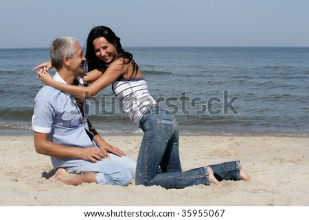 Happy middle aged couple having fun on the beach, enjoying their summer holiday together