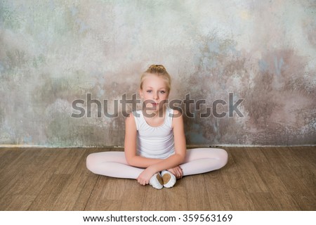 Little ballet dancer doing stretching before class in a white bathing suit, dance, sports, healthy lifestyle, ballet