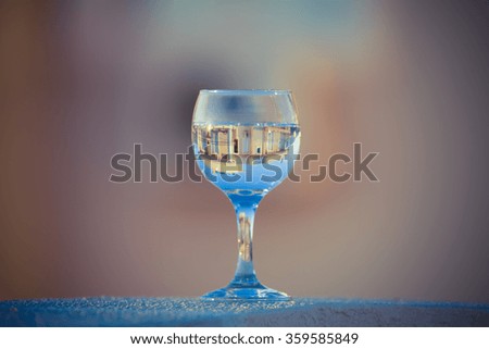 The wineglass with reflection of building on a blurred background. Selective focus. Toned.