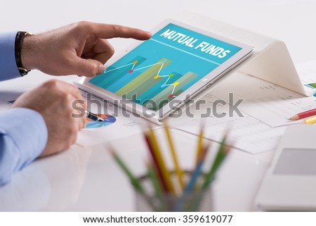 Businessman working on tablet with MUTUAL FUNDS on a screen