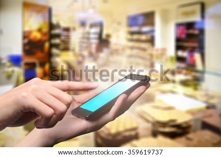Concept of smart phone using in supermarket. Closed up hand of man touch screen.