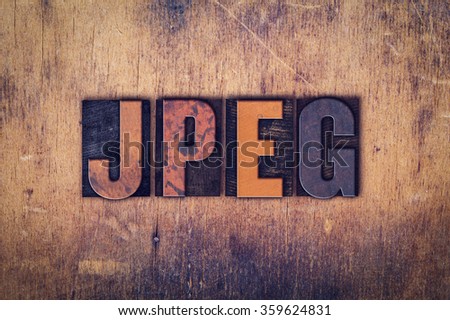 The word "JPEG" written in dirty vintage letterpress type on a aged wooden background.