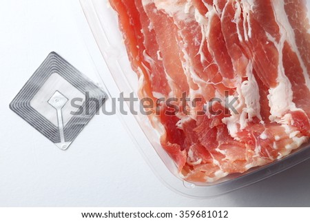 The fresh slide bacon in food grade transparent packaging and rfid tag represent the raw material and meat concept related idea.