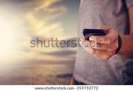 Close-up image of man holding smartphone on the beach background,sunset beach. Texting,video calls,sea front,holidays work,using internet.