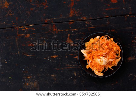 Korean salad made of grated carrots with red fish and onions marinated in the old black cracked background. Copy space. Free space for text, Close-up, top view