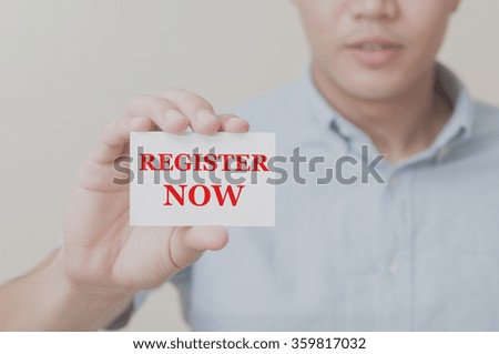 Man's hand showing REGISTER NOW text on the card business card - closeup shot on white background