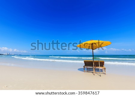 Yellow umbrella and wooden chairs on Hua Hin beach, Thailand Royalty-Free Stock Photo #359847617