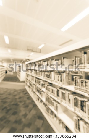 Blurred abstract background of public library interior with aisle of bookshelf with textbooks, literature, seating for students and faculties for reading. Self-study, educational concept/background
