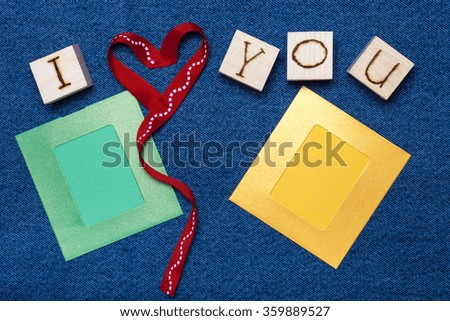 Ribbon heart, love inscription on wooden cubes, photo frame and space for text. Romantic love theme on jeans background.