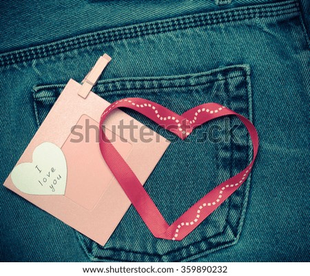 Textile hearts and pink photo frame. Romantic love theme on jeans background. Toned.