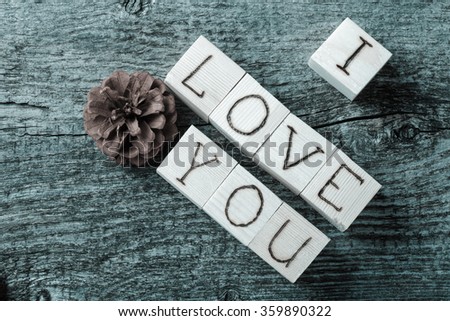 Romantic inscription of letters on light wooden cubes on a old grey wooden background. Toned.