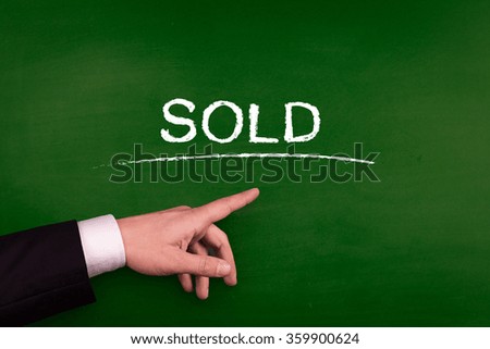 Businessman pointing SOLD word on blackboard