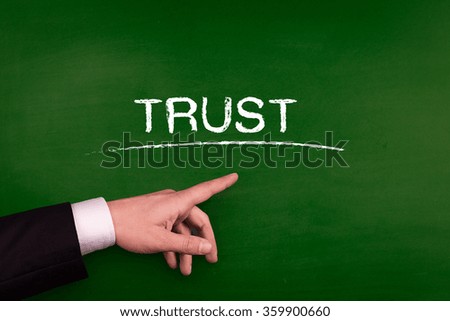 Businessman pointing TRUST word on blackboard
