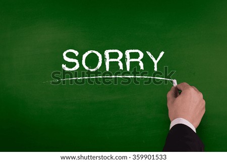 A businessman is writing SORRY concept on blackboard.