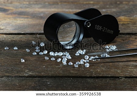cut diamonds with folding magnifier and tweezers on wooden background Royalty-Free Stock Photo #359926538