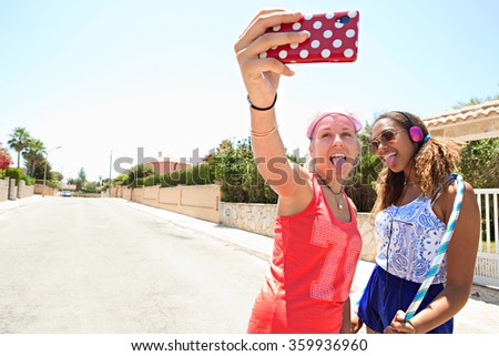 Portrait of diverse teenager friends together pulling faces taking a selfie photo in suburban street in retro colorful clothes having fun, outdoors. Adolescents using smartphone technology, summer.