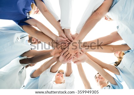 Directly below shot of multiethnic medical team stacking hands over white background Royalty-Free Stock Photo #359949305