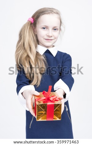 Portrait of cute Caucasian Blond Kid with Gift. Against White Background. Focus on Box in Front. Vertical Image Composition