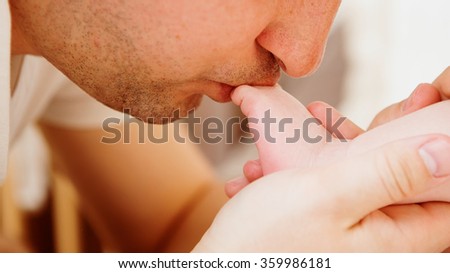father kisses the foot of baby.
