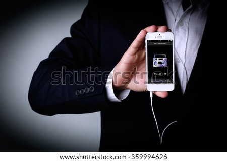 Music smartphone in businessman hand, on grey background
