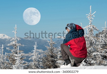 Man photographing the full moon in snow-covered Carpathian mountains. Ukraine