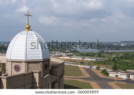 Catholic Basilica of Our Lady of Peace (Basilique Notre-Dame de la Paix) in Yamoussoukro, Cote d'Ivoire, the largest "church" in the world. Hospital construction site on the background. July 2013.