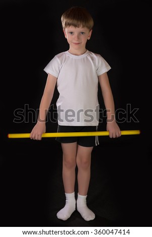 Boy student athlete performs exercises with gymnastic stick in the gym. Demonstrates learning postures sport for gymnastics.