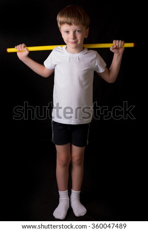 Boy student athlete performs exercises with gymnastic stick in the gym. Demonstrates learning postures sport for gymnastics.