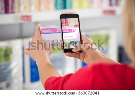 Cropped image of woman photographing capsule packet in store