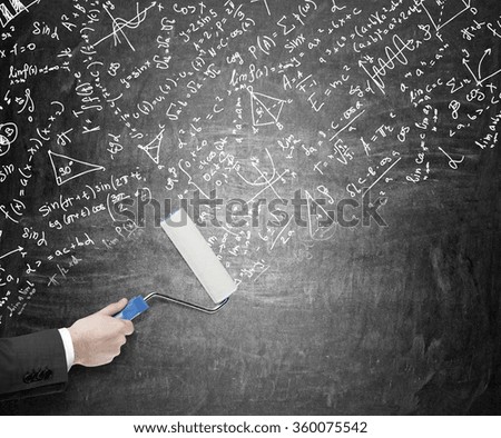 Hand painting on a blackboardl with a roller covering it with mathematic signs, graphs, notes. Concept of giving new ideas