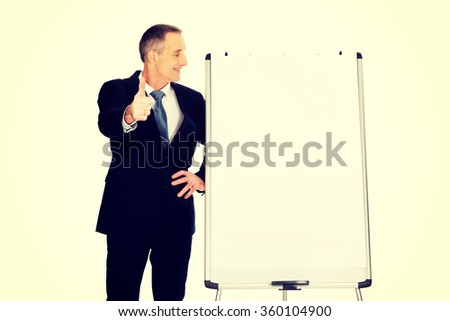 Male executive with ok sign near flip chart