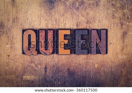 The word "Queen" written in dirty vintage letterpress type on a aged wooden background.